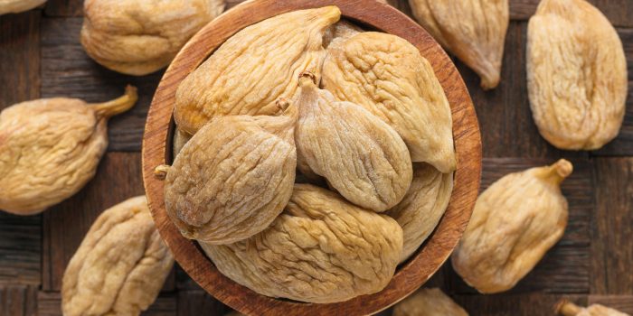 large dried figs in bowl on wooden table background.