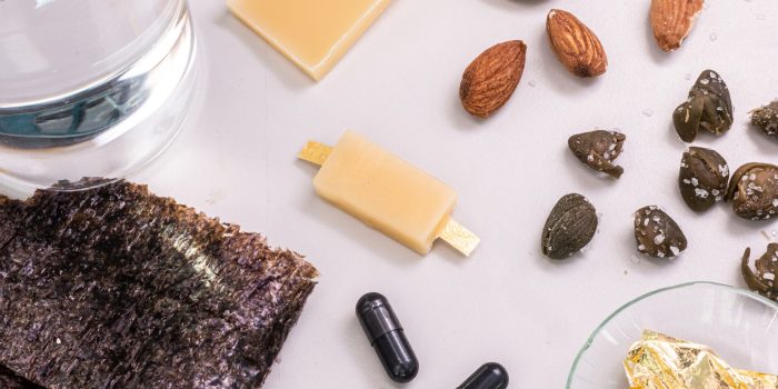 The edible battery (center), surrounded by the ingredients used to make it (clockwise from top right): almonds, capers, edible gold foil, activated carbon, nori algae, water electrolyte, beeswax. Photo: G. Berretta / Istituto Italiano di Tecnologia - © IIT, all rights reserved.